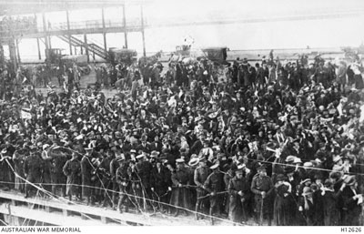 Photo of a crowded dock with people cheering embarking troops