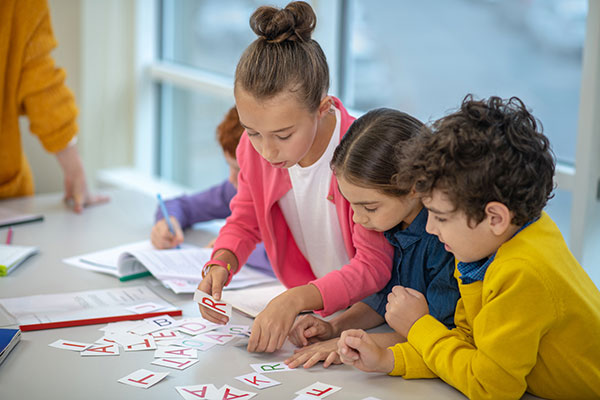 Children organising letters on a table top